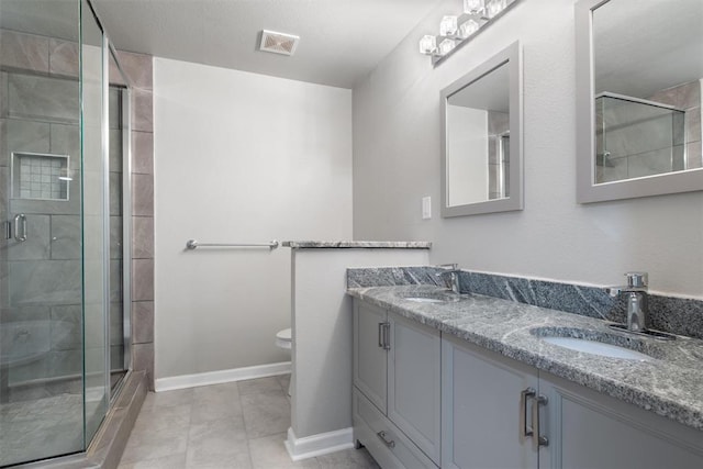 bathroom with tile patterned flooring, vanity, toilet, and a shower with door