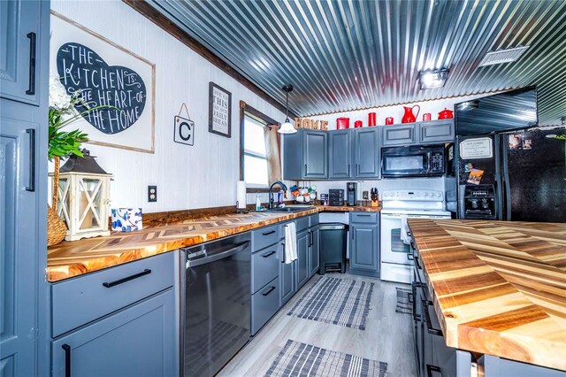 kitchen featuring light hardwood / wood-style floors, crown molding, sink, black appliances, and butcher block countertops