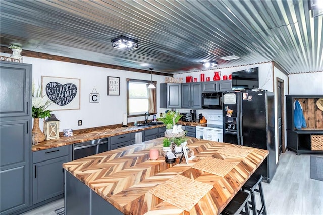 kitchen featuring sink, wood counters, light hardwood / wood-style floors, a kitchen island, and black appliances