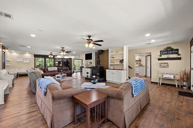 living room with a wood stove, ceiling fan, and hardwood / wood-style flooring