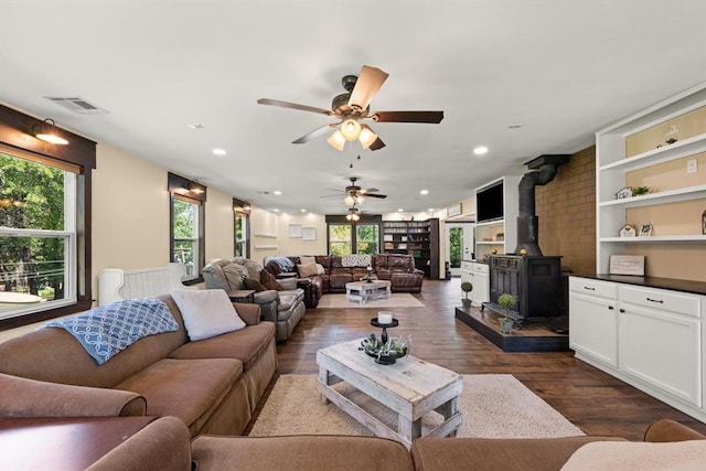 living room with ceiling fan, dark hardwood / wood-style flooring, and a wood stove