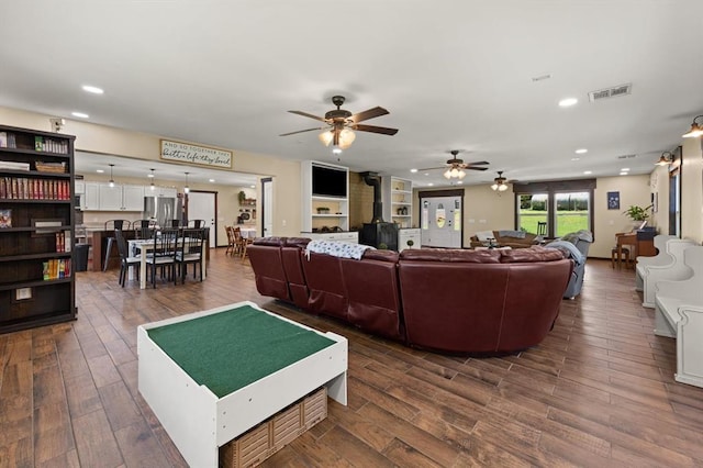 living room with hardwood / wood-style flooring, ceiling fan, and a wood stove