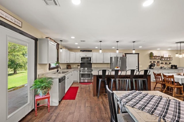 kitchen featuring a kitchen island, hanging light fixtures, dark hardwood / wood-style floors, and appliances with stainless steel finishes