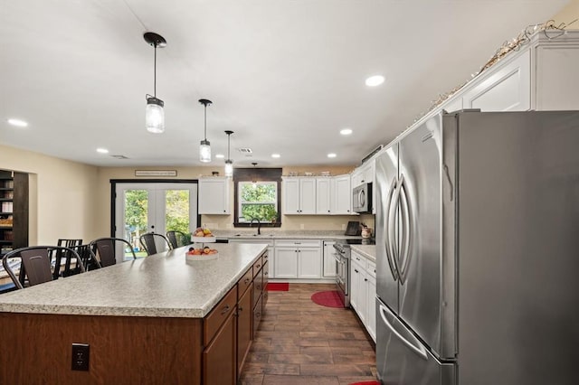 kitchen featuring pendant lighting, dark wood-type flooring, appliances with stainless steel finishes, a kitchen island, and white cabinetry