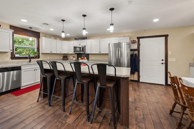 kitchen featuring appliances with stainless steel finishes, a center island, white cabinetry, and hanging light fixtures