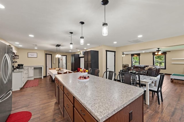 kitchen featuring ceiling fan, dark hardwood / wood-style floors, a center island, and stainless steel refrigerator