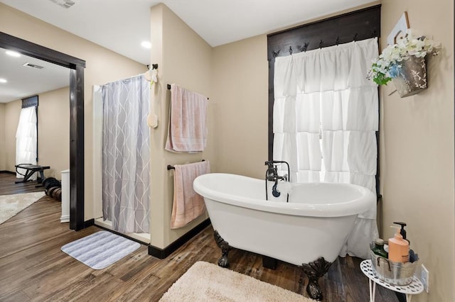 bathroom with a tub to relax in and hardwood / wood-style flooring