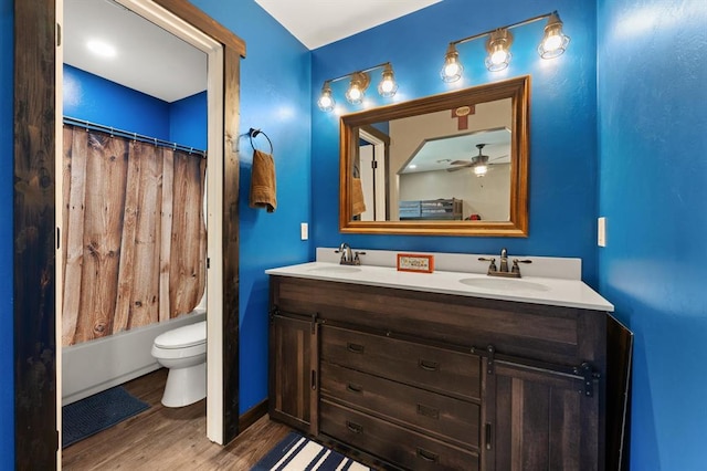 full bathroom with ceiling fan, wood-type flooring, toilet, shower / bath combo with shower curtain, and vanity