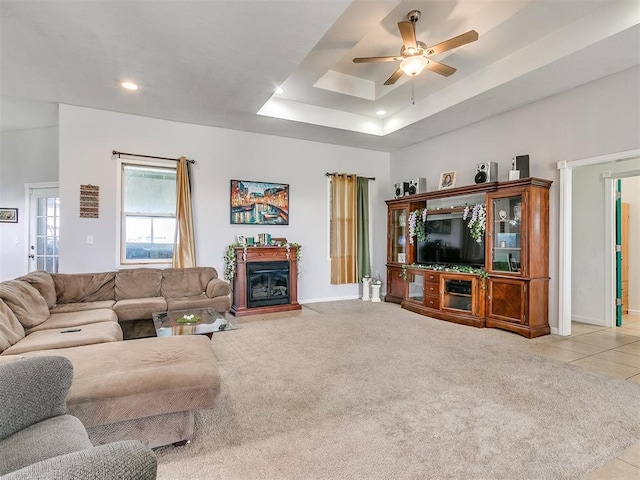 living room with light carpet, a raised ceiling, and ceiling fan