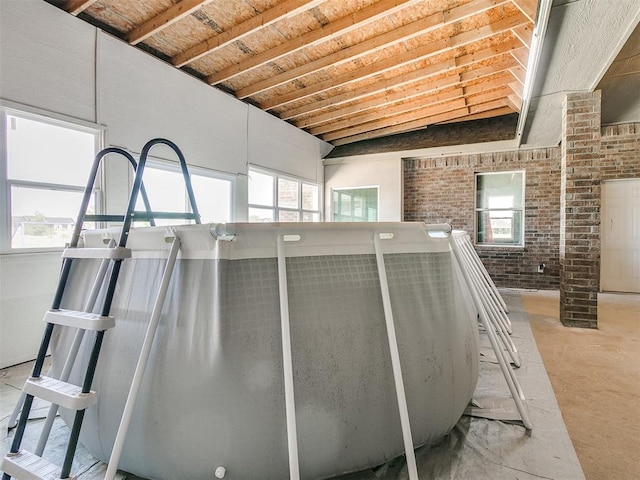 interior space featuring lofted ceiling and brick wall