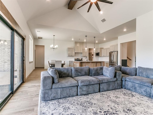 living room with high vaulted ceiling, ceiling fan with notable chandelier, sink, light wood-type flooring, and beam ceiling