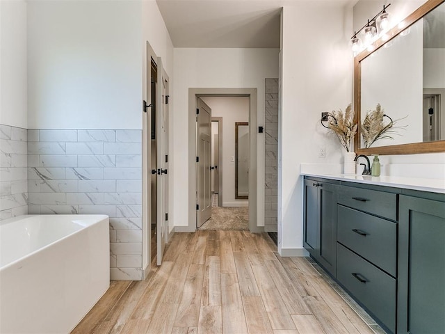 bathroom with hardwood / wood-style floors, vanity, a bathing tub, and tile walls