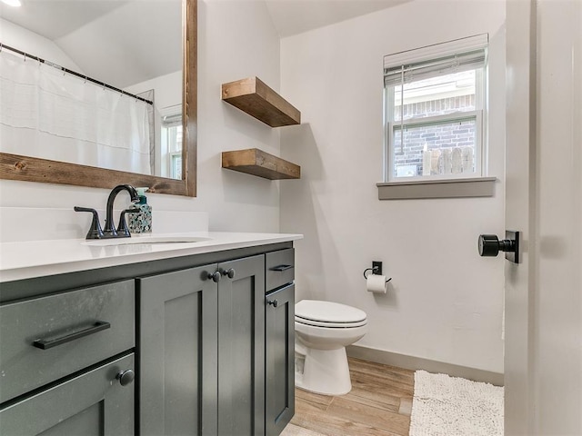 bathroom with hardwood / wood-style floors, vanity, toilet, and vaulted ceiling