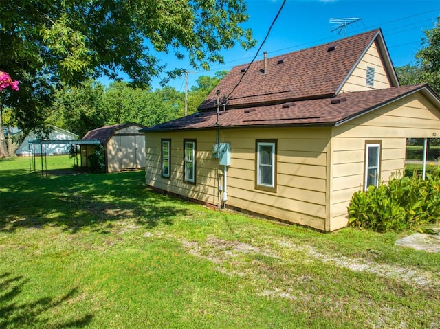 back of house featuring a lawn and a storage shed