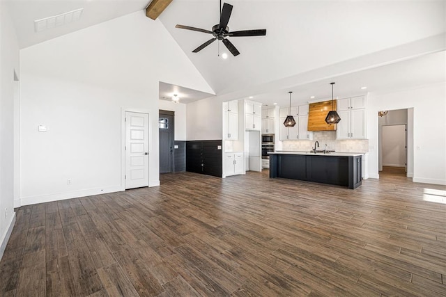 unfurnished living room with visible vents, beamed ceiling, high vaulted ceiling, a ceiling fan, and dark wood-style flooring