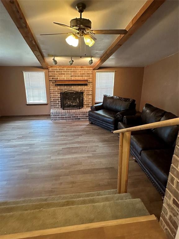 living room with ceiling fan, beam ceiling, wood-type flooring, and a fireplace