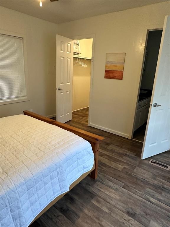 bedroom featuring a walk in closet, dark hardwood / wood-style floors, and a closet