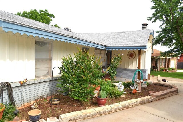 5932 NW 62nd Ter, Oklahoma City, OK 73122 - view of side of home featuring a shingled roof and a chimney