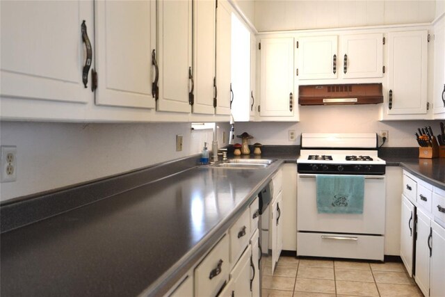 5932 NW 62nd Ter, Oklahoma City, OK 73122 - kitchen with white range with gas cooktop, under cabinet range hood, dark countertops, light tile patterned flooring, and white cabinetry