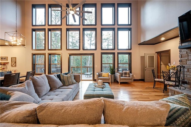 living room featuring a fireplace, a high ceiling, light hardwood / wood-style floors, and plenty of natural light