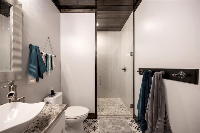 bathroom with tile patterned floors, a shower with door, vanity, and toilet