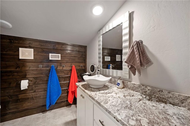 bathroom featuring tile patterned flooring, vanity, and lofted ceiling