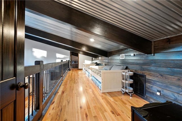 interior space with beamed ceiling, light hardwood / wood-style floors, and wooden walls