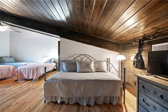 bedroom with light wood-type flooring, ceiling fan, wooden walls, beam ceiling, and wooden ceiling