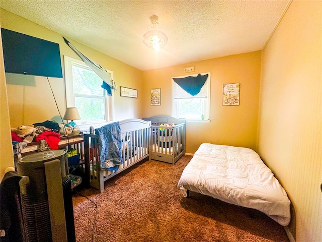 carpeted bedroom featuring multiple windows and a textured ceiling