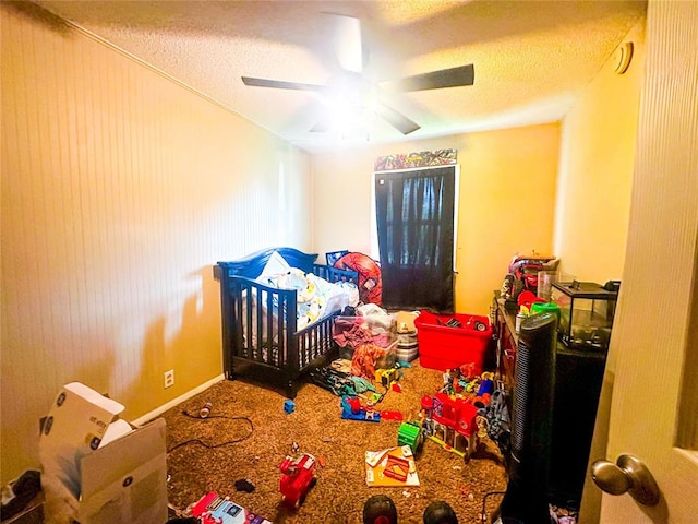 bedroom featuring carpet, ceiling fan, a textured ceiling, and a nursery area