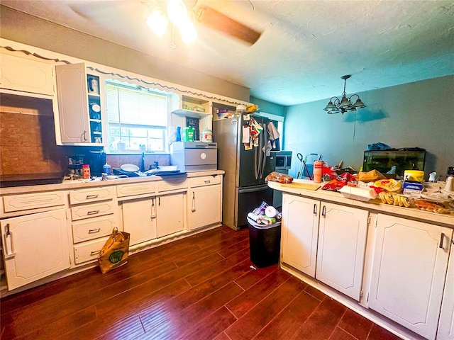 kitchen featuring stainless steel refrigerator, dark hardwood / wood-style flooring, white cabinets, and a chandelier