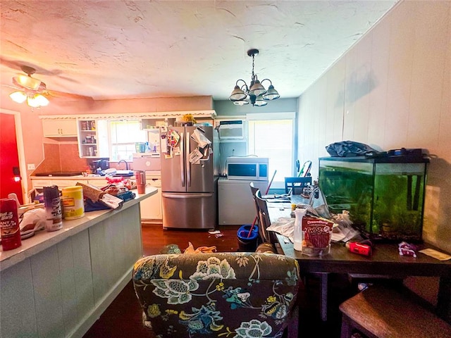 interior space featuring a wall mounted air conditioner, ceiling fan with notable chandelier, a healthy amount of sunlight, and stainless steel appliances