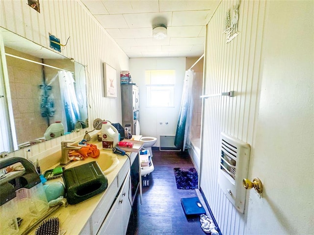 full bathroom featuring shower / bath combination with curtain, vanity, heating unit, hardwood / wood-style flooring, and toilet