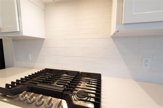 room details with stovetop, decorative backsplash, and white cabinetry