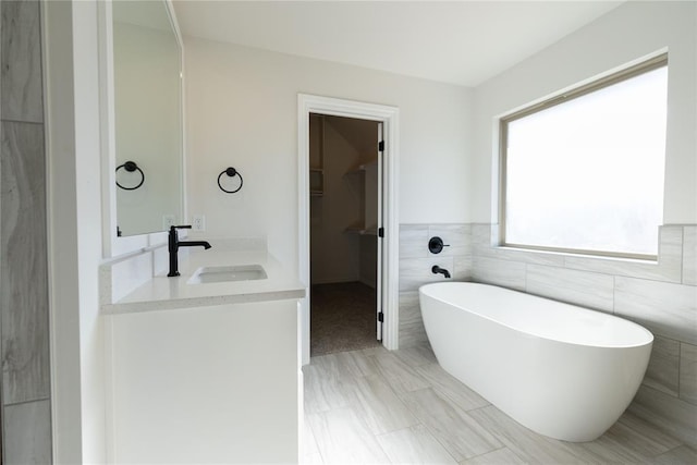 bathroom with vanity, tile walls, and a bathing tub