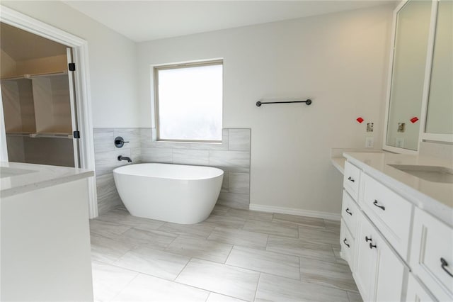 bathroom with tile walls, vanity, and a bathing tub