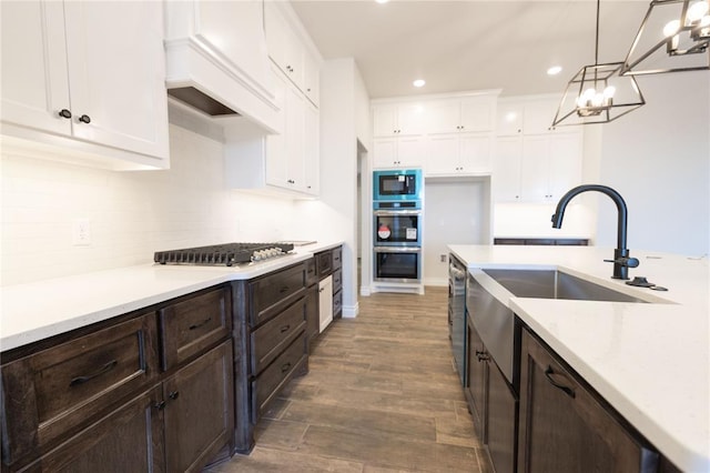 kitchen with sink, hanging light fixtures, stainless steel appliances, tasteful backsplash, and white cabinets