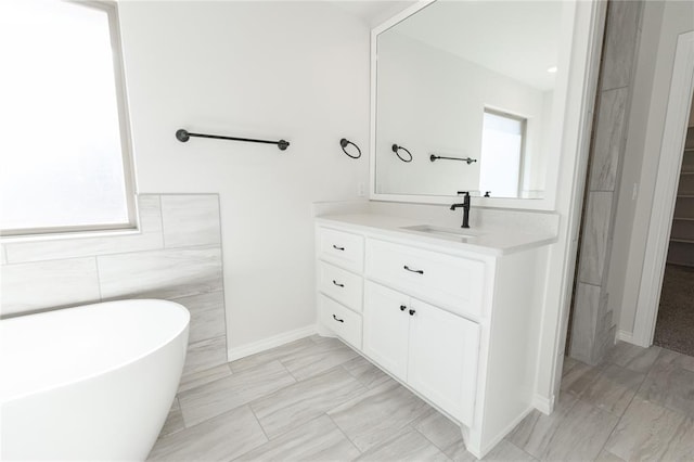 bathroom with vanity, a healthy amount of sunlight, tile walls, and a bathtub