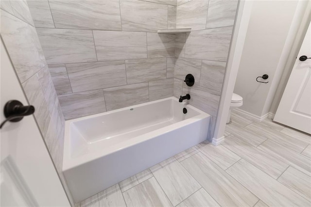 bathroom with tiled shower / bath combo and toilet