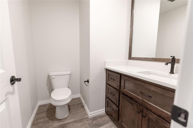 bathroom featuring wood-type flooring, toilet, and vanity