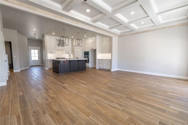 unfurnished living room with hardwood / wood-style flooring, beam ceiling, coffered ceiling, and sink