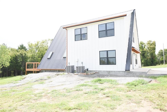 rear view of house with board and batten siding and central AC