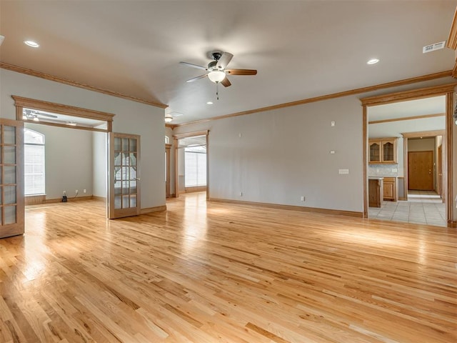 spare room featuring french doors, light hardwood / wood-style flooring, ceiling fan, and crown molding