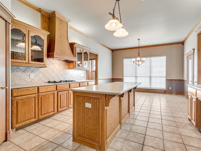 kitchen featuring gas cooktop, custom range hood, light tile patterned floors, decorative light fixtures, and a kitchen island