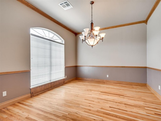 spare room featuring light hardwood / wood-style floors, crown molding, and an inviting chandelier