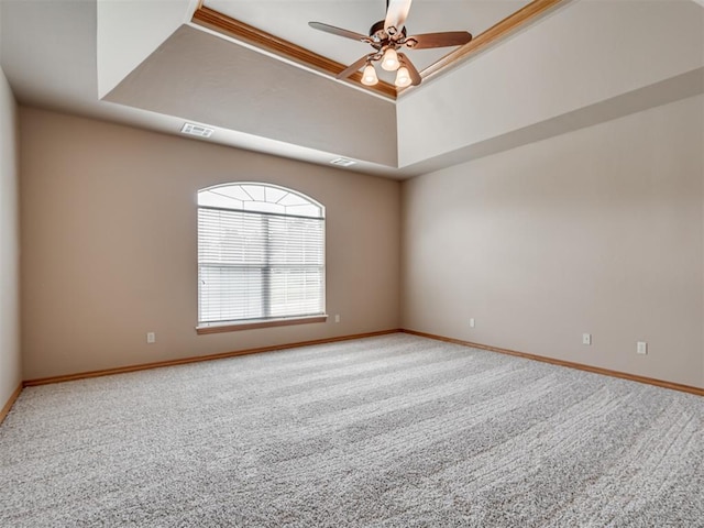 unfurnished room with a raised ceiling, ceiling fan, and carpet