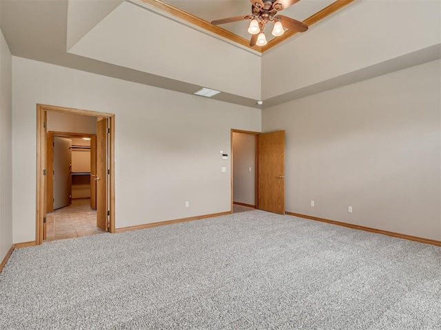 unfurnished bedroom featuring a raised ceiling, connected bathroom, ceiling fan, and light colored carpet