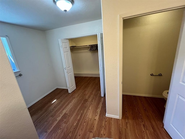 unfurnished bedroom featuring a closet and dark wood-type flooring