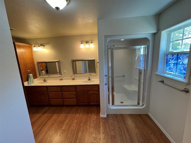 bathroom with a shower with door, wood-type flooring, and a textured ceiling