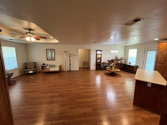 living room featuring ceiling fan with notable chandelier, a textured ceiling, and dark hardwood / wood-style flooring